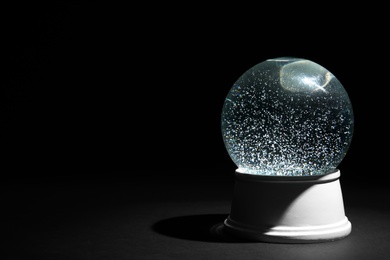 Photo of Magical empty snow globe on dark background. Space for text