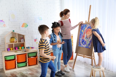 Photo of Children with female teacher at painting lesson indoors