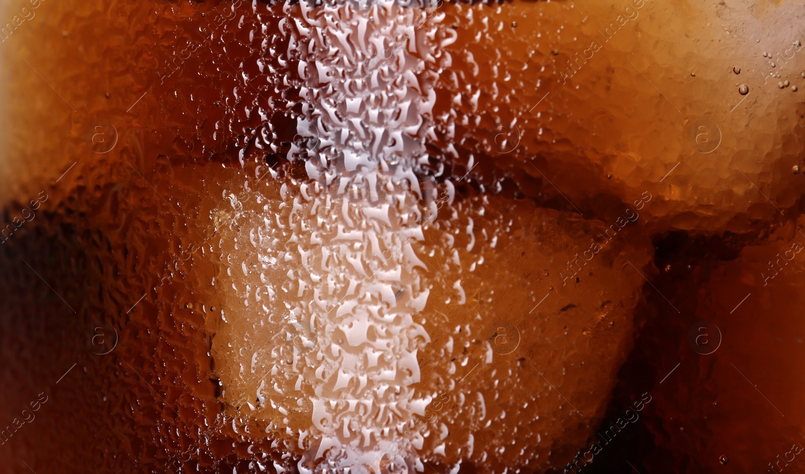 Photo of Glass of refreshing drink with ice cubes as background, closeup