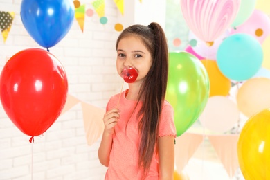 Photo of Happy girl near bright balloons at birthday party indoors