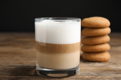 Photo of Delicious latte macchiato and cookies on wooden table