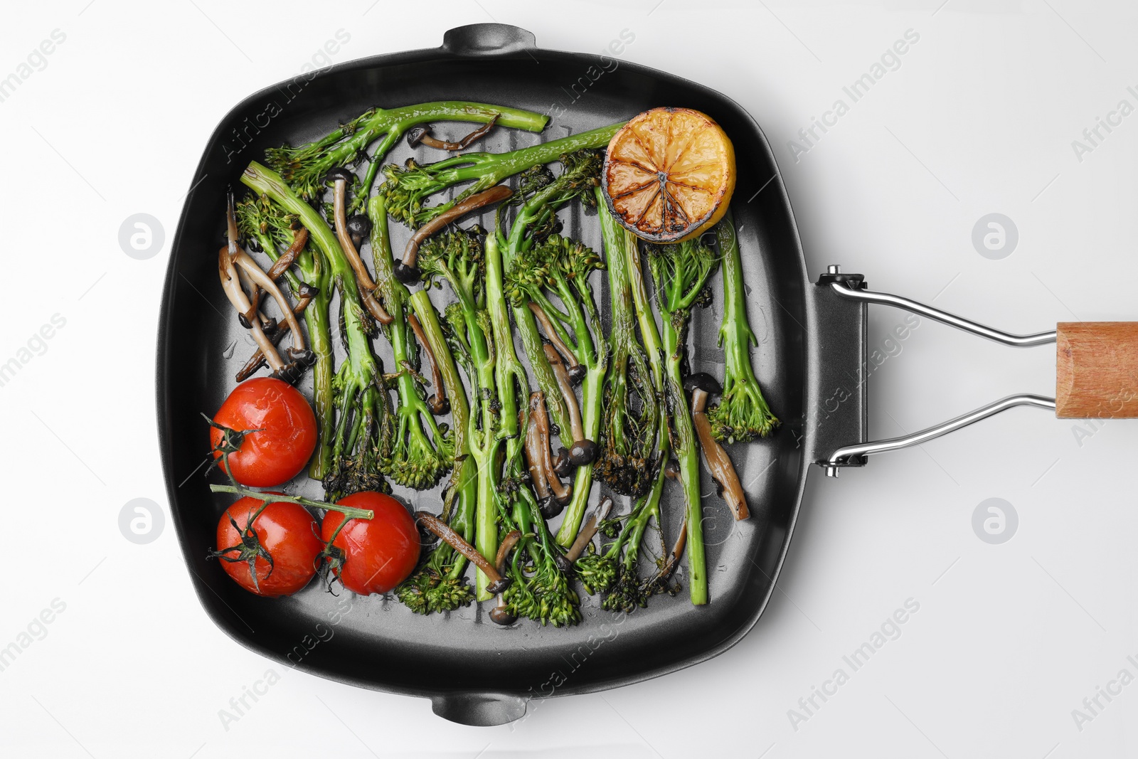 Photo of Grill pan with tasty cooked broccolini, mushrooms, tomatoes and lemon on white background, top view