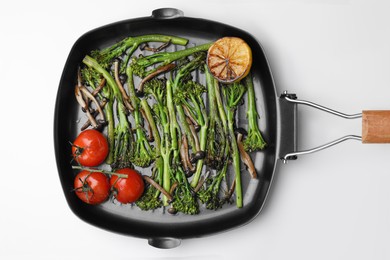 Photo of Grill pan with tasty cooked broccolini, mushrooms, tomatoes and lemon on white background, top view