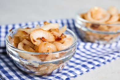 Photo of Tasty fried onion in glass bowl on table, closeup
