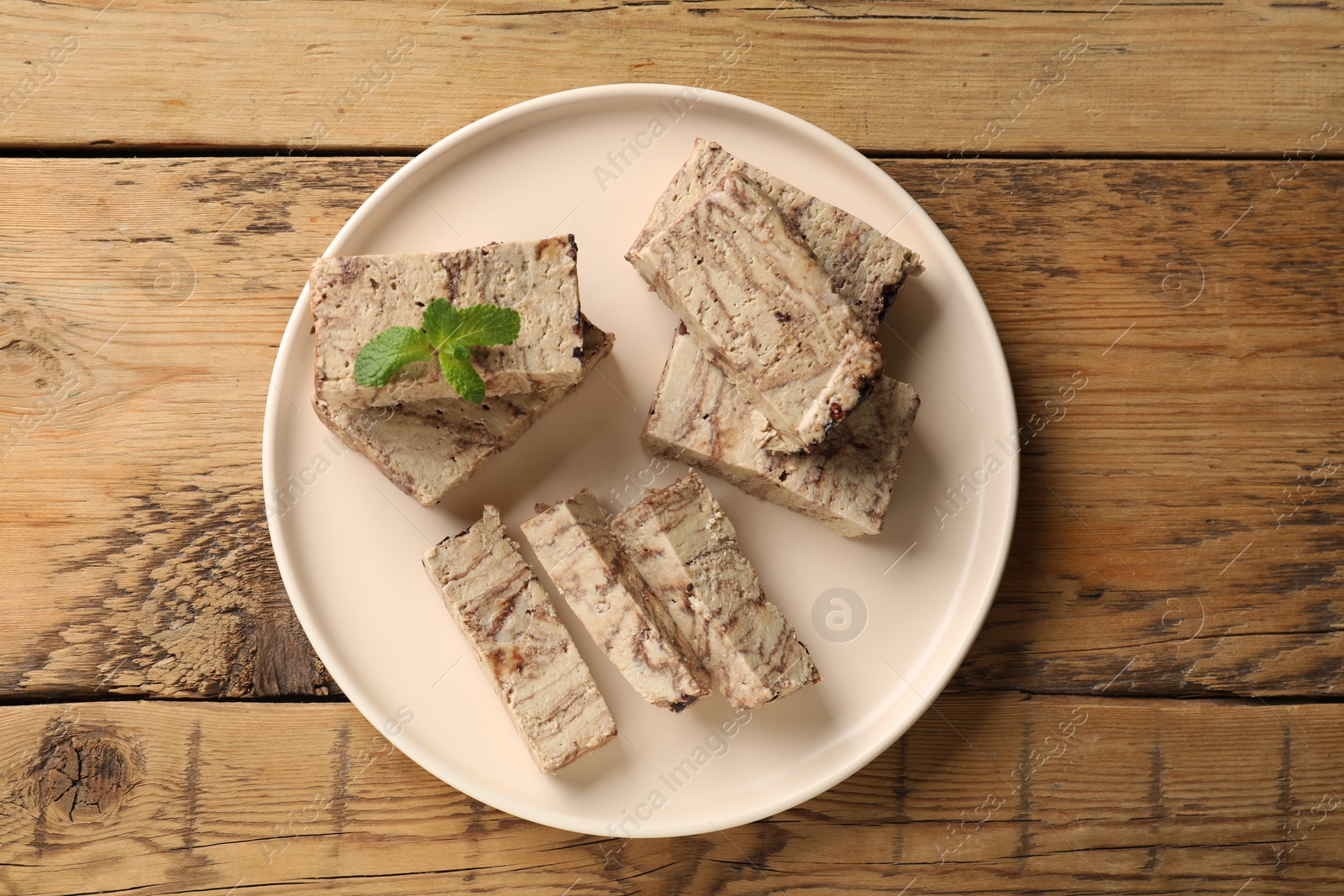 Photo of Tasty chocolate halva with mint on wooden table, top view