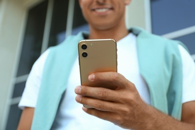 Photo of Man using modern mobile phone outdoors, closeup