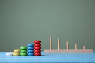 Photo of Stacking and counting game pieces on light blue wooden table against grey wall, space for text. Motor skills development