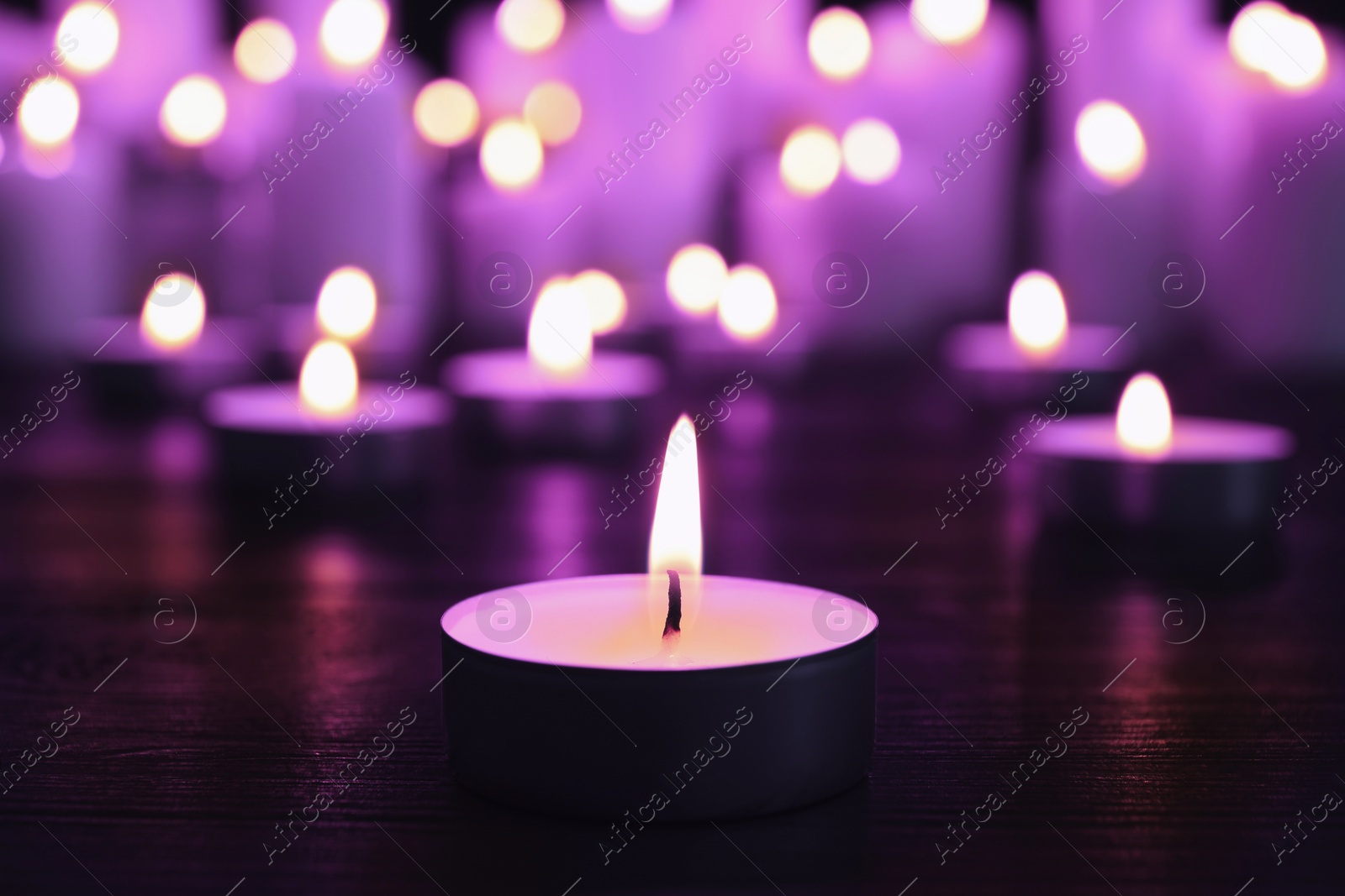 Image of Burning violet candle on black background, closeup. Funeral attributes