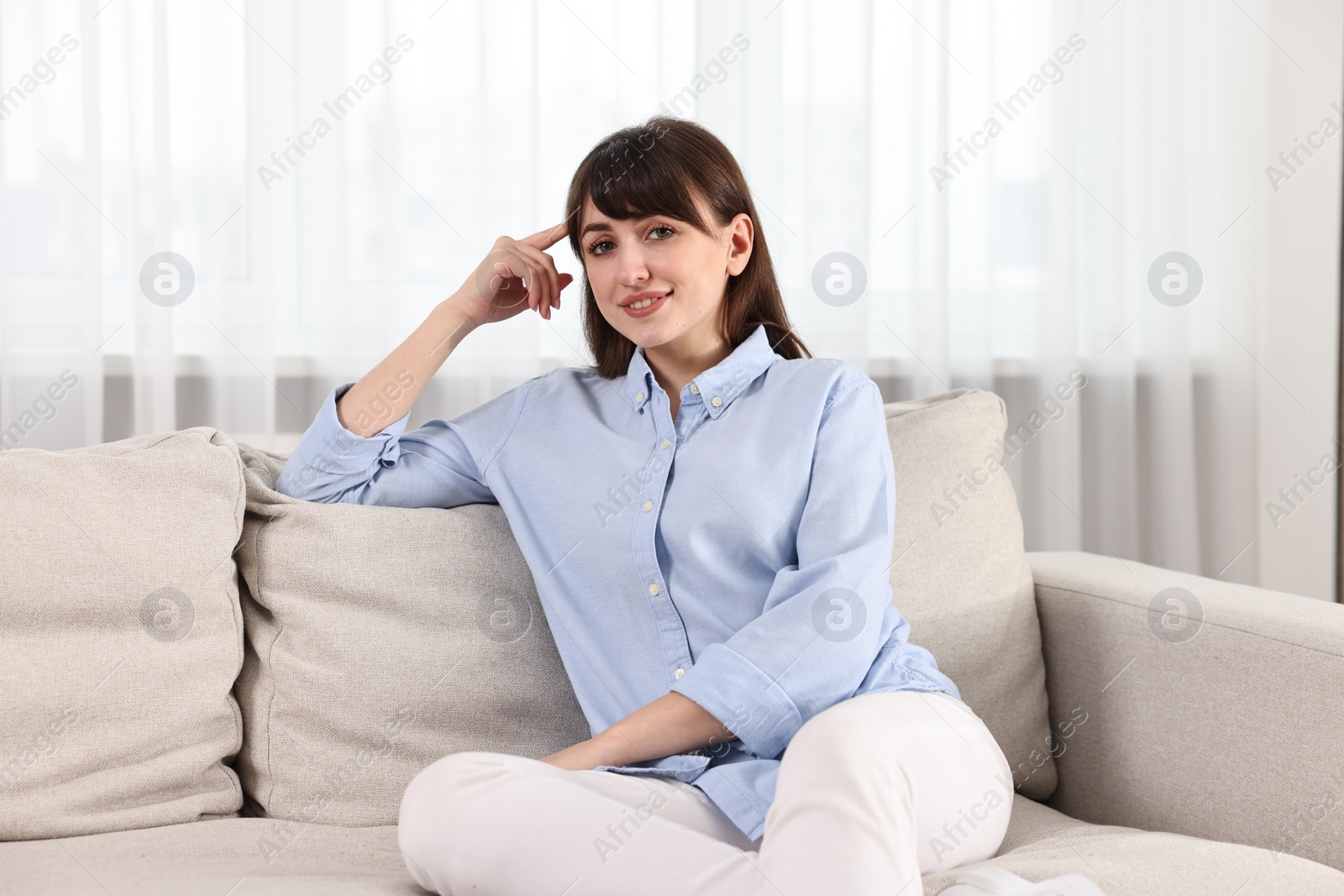 Photo of Beautiful young housewife on sofa at home
