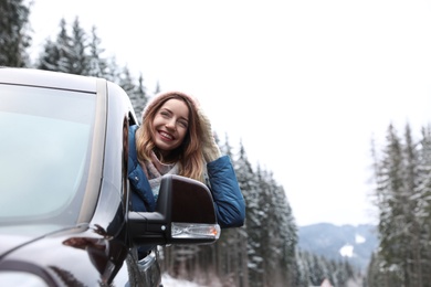 Young woman driving car and looking out of window on road. Winter vacation