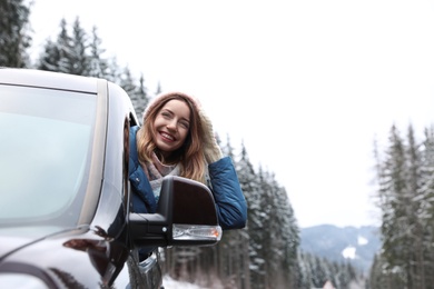 Photo of Young woman driving car and looking out of window on road. Winter vacation