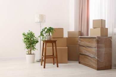 Photo of Boxes, lamp and chest of drawers wrapped in stretch film indoors