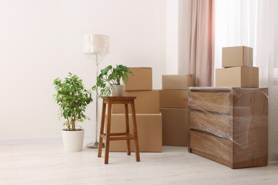 Boxes, lamp and chest of drawers wrapped in stretch film indoors