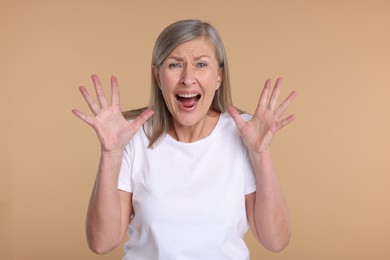 Photo of Portrait of surprised senior woman on beige background