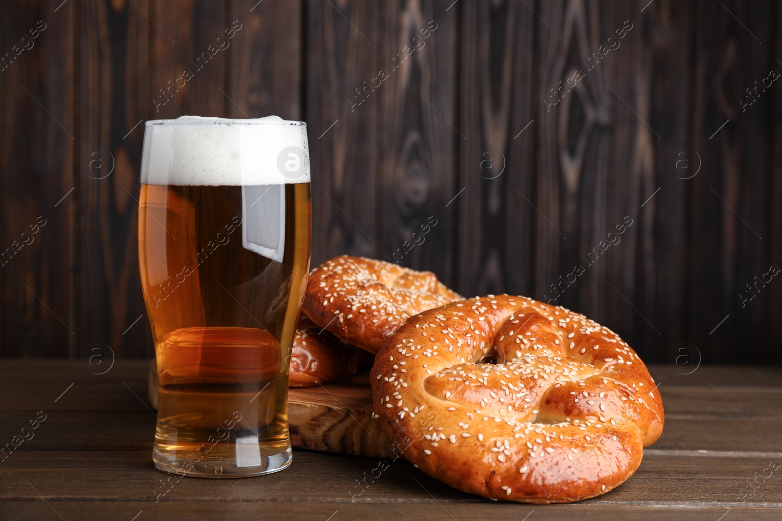 Photo of Tasty pretzels and glass of beer on wooden table