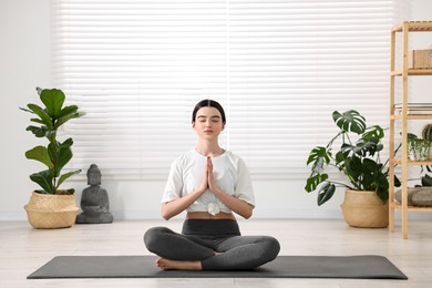 Beautiful girl meditating on mat in yoga studio