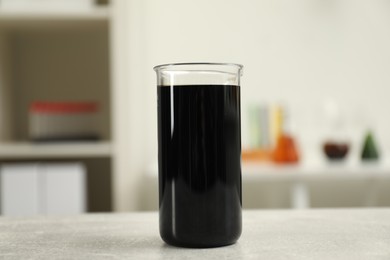 Beaker with black crude oil on light grey table
