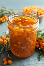 Delicious sea buckthorn jam and fresh berries on blue wooden table