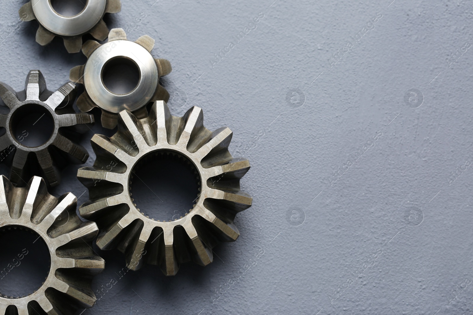 Photo of Different stainless steel gears on grey background, flat lay. Space for text