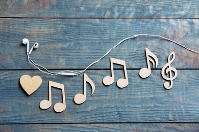 Flat lay composition with music notes and earphones on wooden background