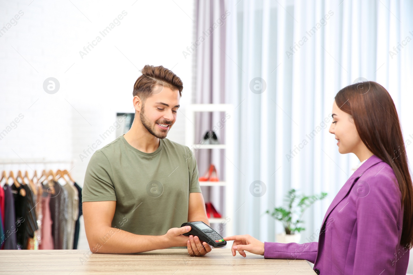 Photo of Woman using terminal for contactless payment in shop