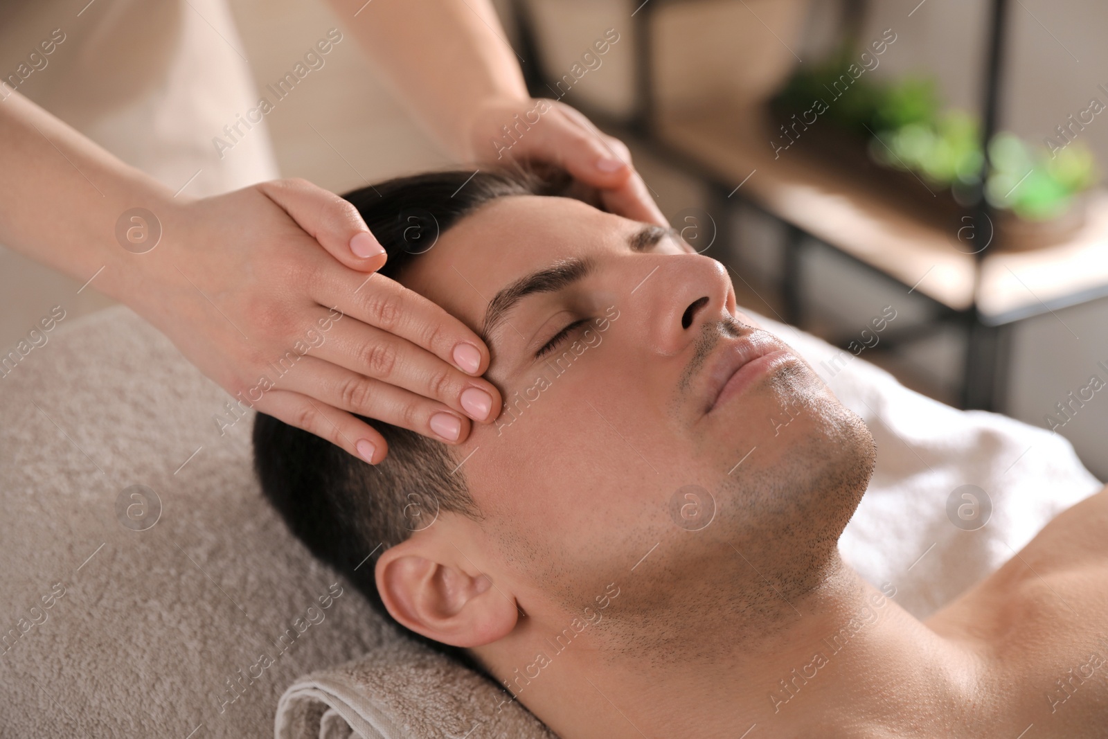 Photo of Man receiving facial massage in beauty salon, closeup