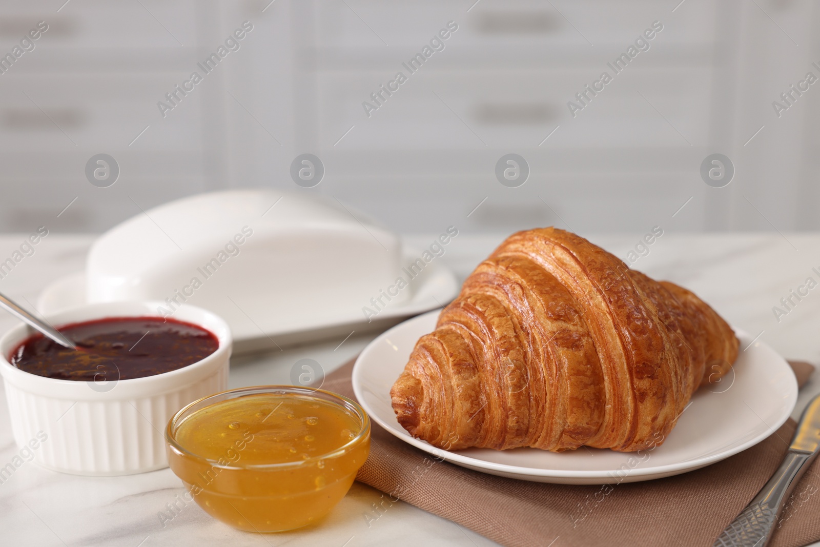 Photo of Breakfast time. Fresh croissant, jam and honey on white table