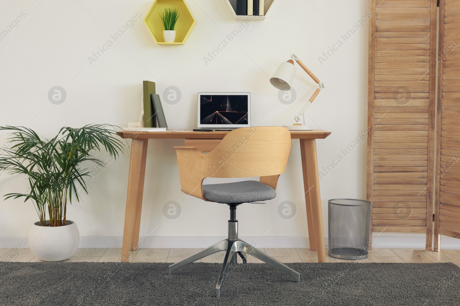 Photo of Cozy workspace with modern laptop on desk and comfortable chair at home