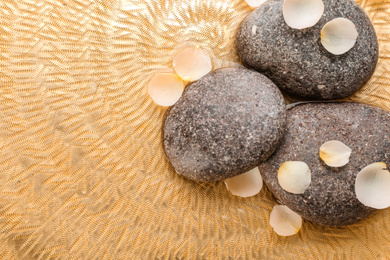 Photo of Stones and flower petals in water, top view with space for text. Zen lifestyle