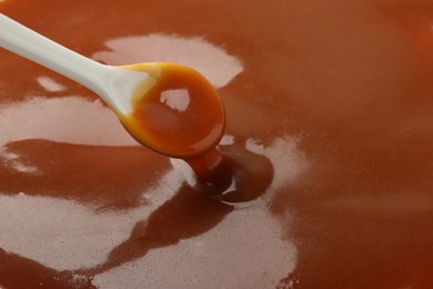 Photo of Taking tasty salted caramel with spoon, closeup. Space for text