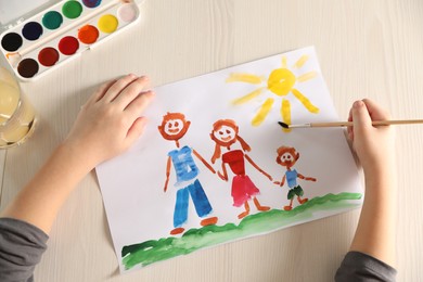 Photo of Little boy drawing picture at wooden table, top view. Child`s art