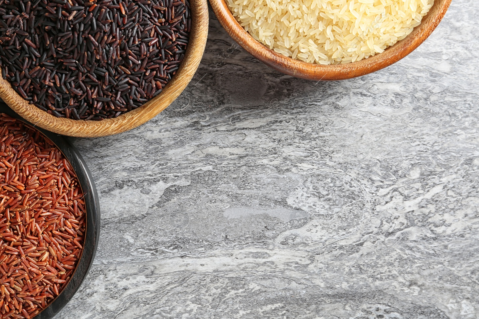 Photo of Flat lay composition with brown and other types of rice in bowls on grunge background. Space for text