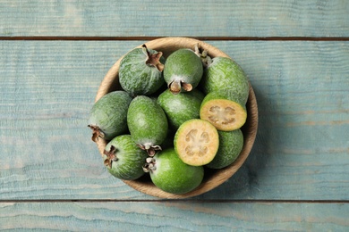 Fresh green feijoa fruits in bowl on blue wooden table, top view