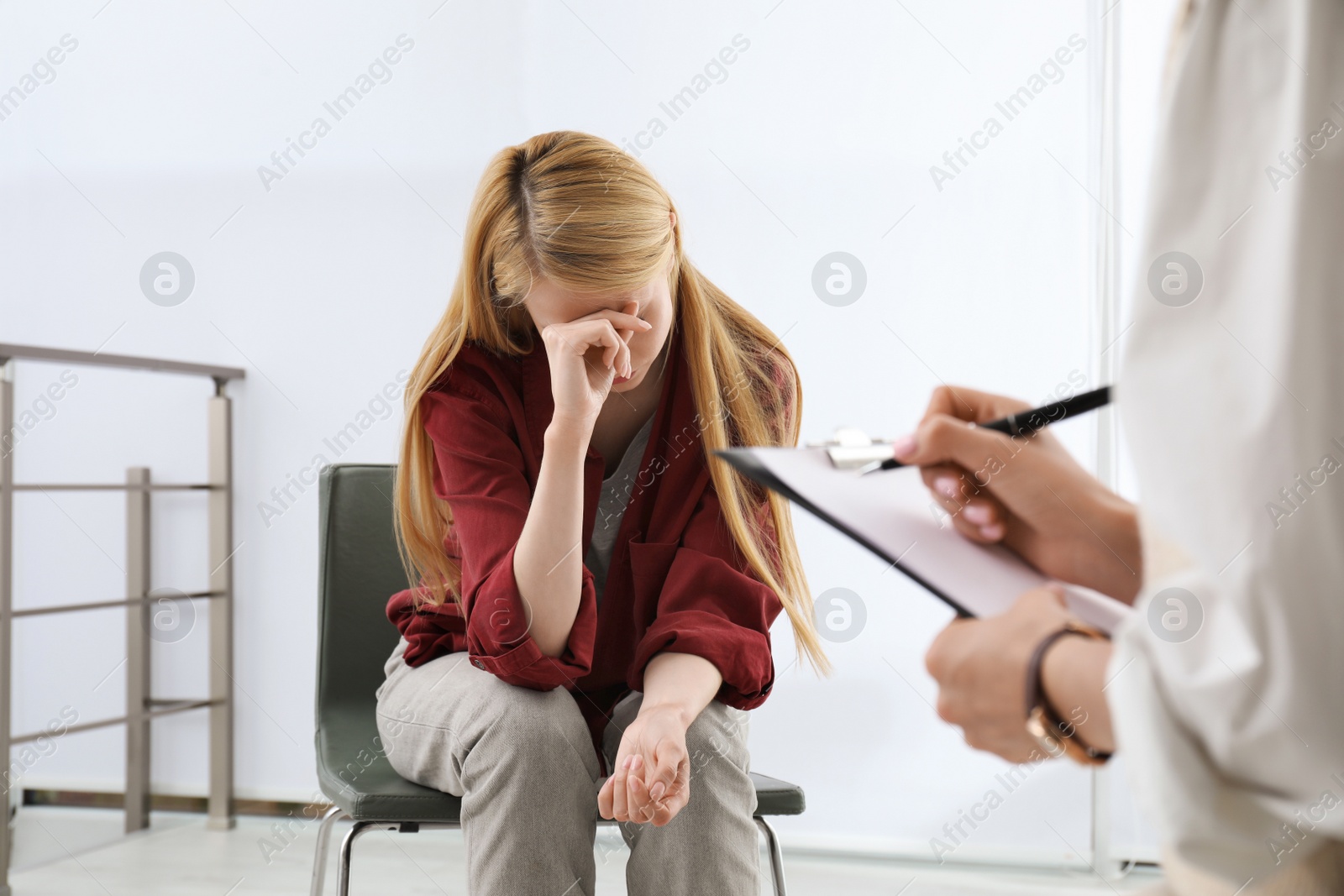 Photo of Psychotherapist working with drug addicted young woman indoors