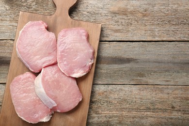 Photo of Pieces of raw pork meat on wooden table, top view. Space for text