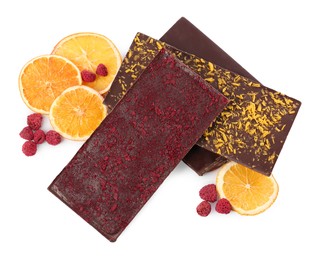 Photo of Chocolate bars with freeze dried fruits, raspberries and orange slices on white background, top view