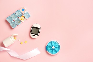 Digital glucometer, pills and ribbon on pink background, flat lay with space for text. Medical gift