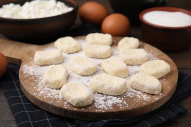 Photo of Making lazy dumplings. Board with cut dough and ingredients on wooden table, closeup