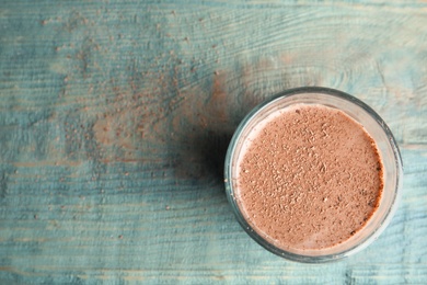 Photo of Glass with tasty chocolate milk and space for text on wooden background, top view. Dairy drink