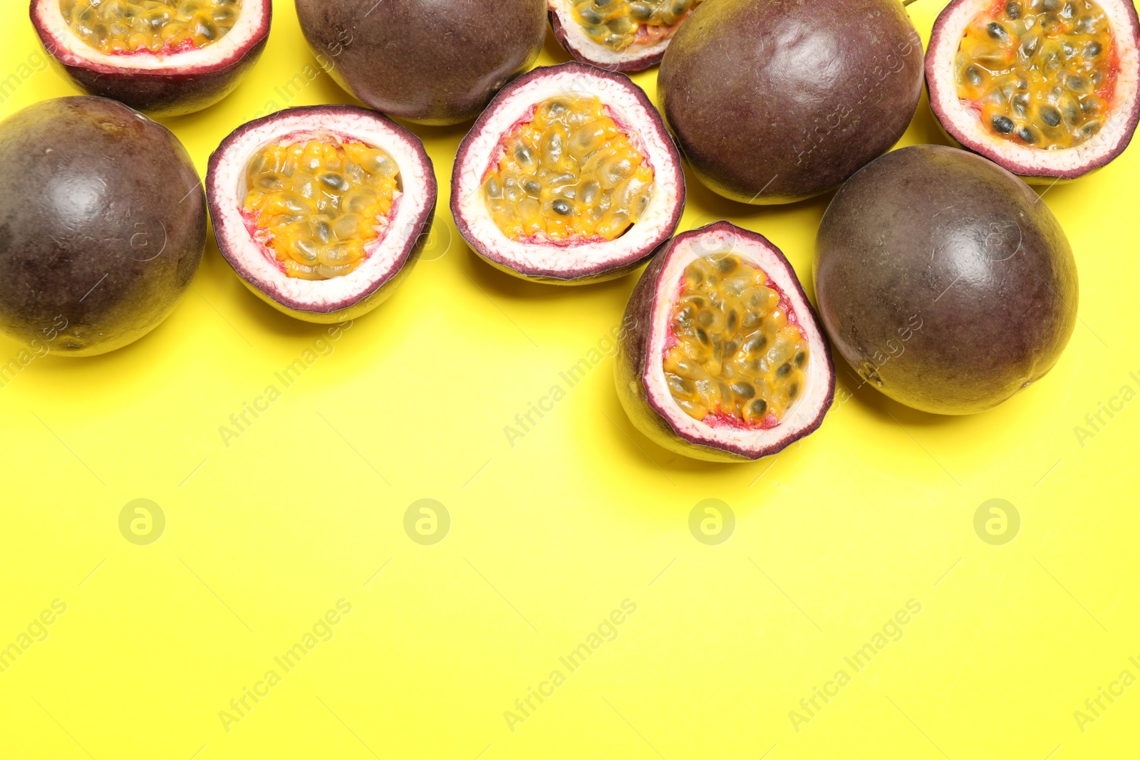 Photo of Fresh ripe passion fruits (maracuyas) on yellow background, flat lay. Space for text