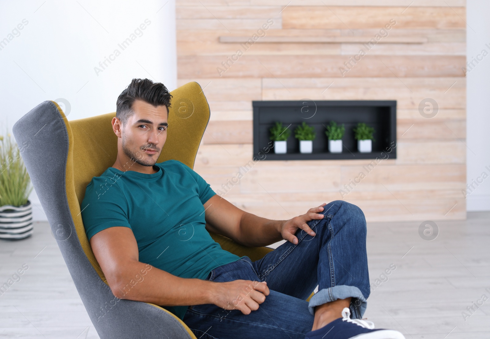 Photo of Portrait of handsome young man sitting in armchair at home