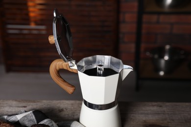 Photo of Aromatic coffee in moka pot on wooden table, closeup