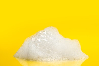 Photo of Drop of fluffy bath foam on yellow background