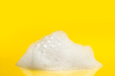 Drop of fluffy bath foam on yellow background