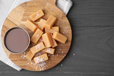 Yummy caramel candies and sea salt on wooden table, top view. Space for text