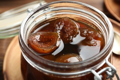 Photo of Jar of tasty sweet fig jam on table, closeup