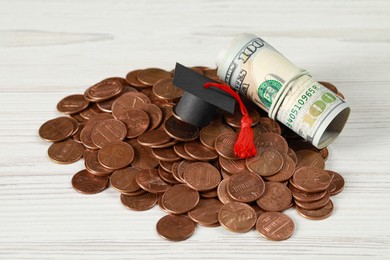 Photo of Scholarship concept. Graduation cap, coins and dollar banknotes on white wooden table