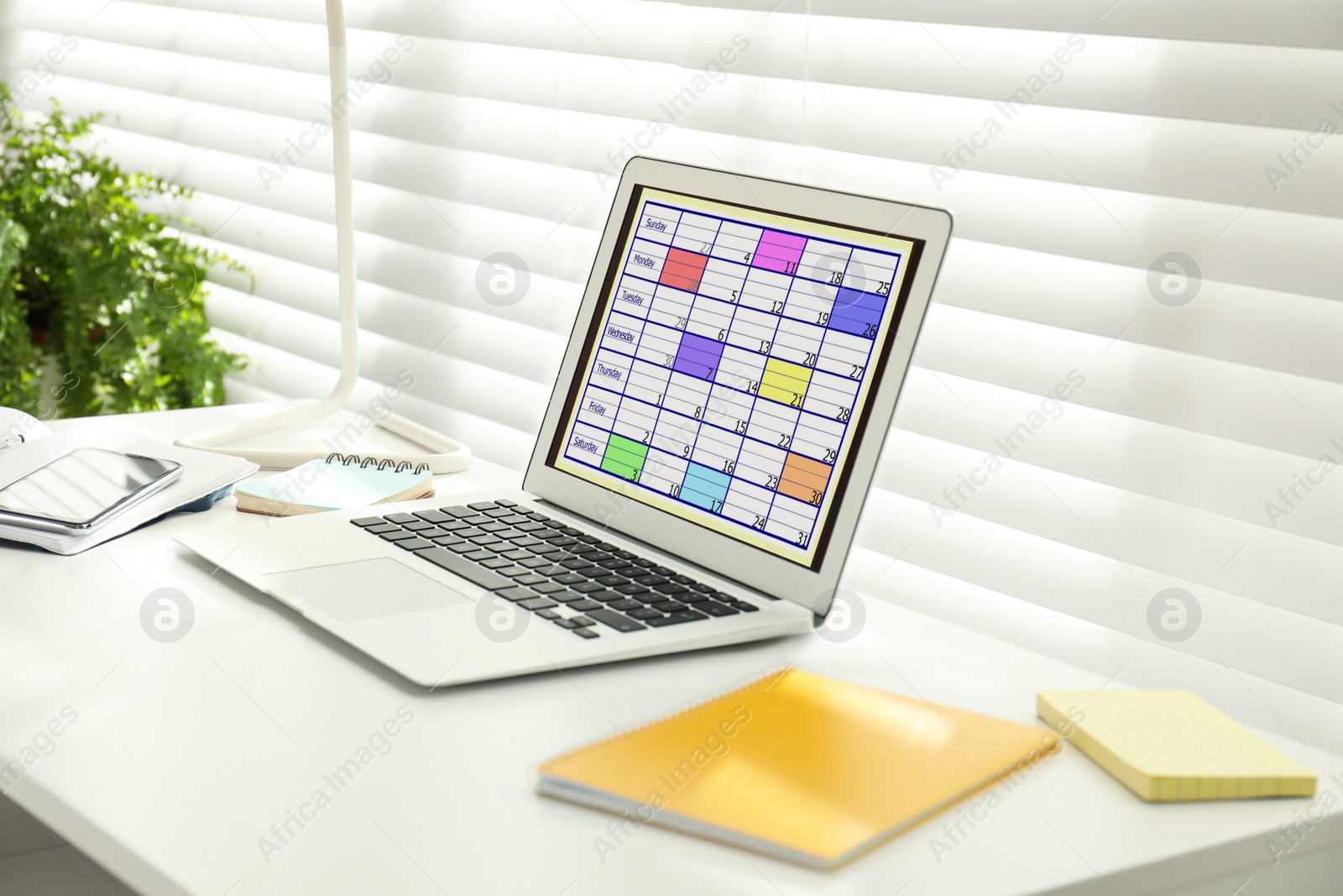 Photo of Modern laptop with calendar app at table in office