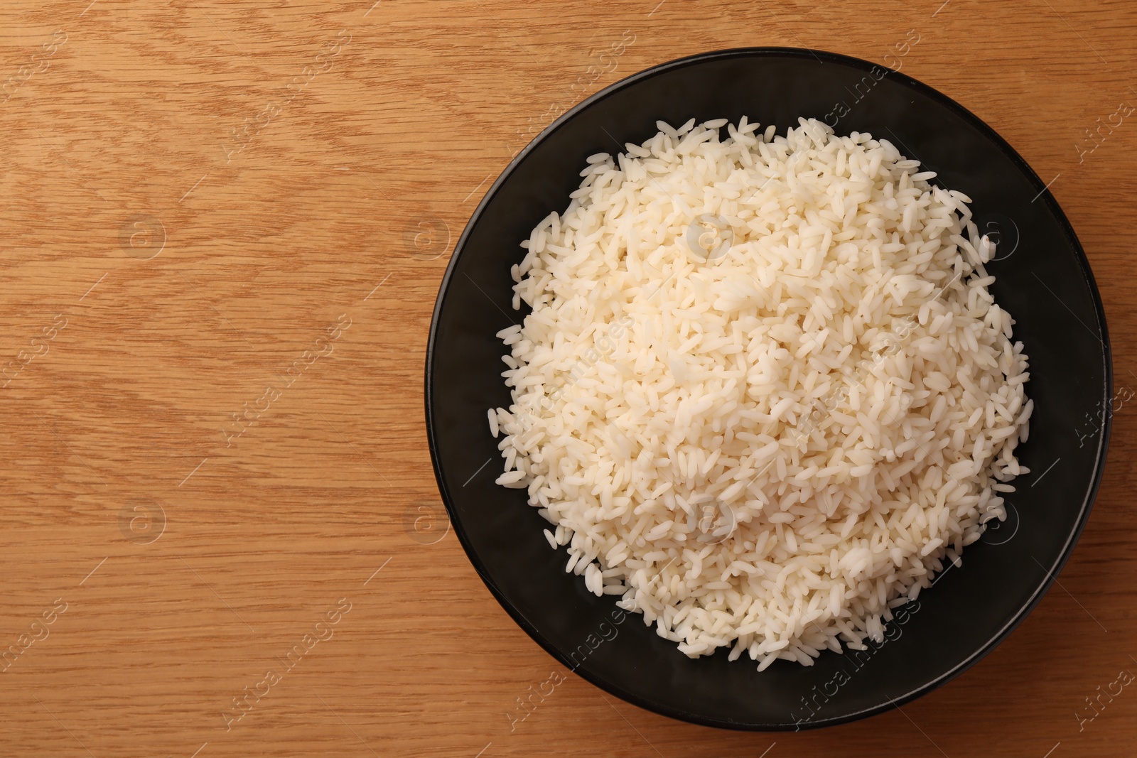 Photo of Plate with delicious rice on wooden table, top view. Space for text