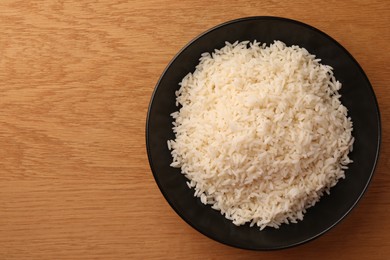 Photo of Plate with delicious rice on wooden table, top view. Space for text